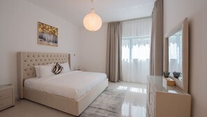 Camera da letto moderna con una testiera trapuntata, un letto grande, un comodino, una cassettiera, uno specchio e una lampada a sospensione.