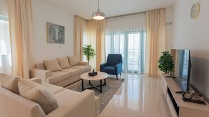 Un soggiorno moderno con divano, poltrona, tavolino, televisore e tende.