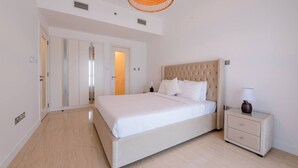 Un dormitori amb llit, taulella de nit i una porta que dona a una altra habitació.