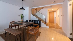 Un interior modern amb zona de menjador, escala i vista exterior.