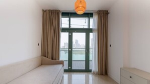 Habitació minimalista amb un sofà, una petita arca i vista a un cos d'aigua a través d'una porta de vidre.
