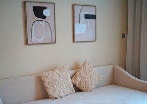 Ein Zimmer mit einer Couch, zwei abstrakten Gemälden und zwei gemusterten Kissen.