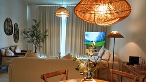 A living room with a sofa, a dining table with plates, a vase with flowers, and two hanging lamps. - Beach View 3BR Duplex Retreat in Al Reem (Abu Dhabi)