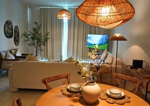 A living room with a sofa, a dining table with plates, a vase with flowers, and two hanging lamps. - Beach View 3BR Duplex Retreat in Al Reem (Abu Dhabi)