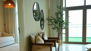 A living room with a sofa, two armchairs, a large window, and a potted plant. - Beach View 3BR Duplex Retreat in Al Reem (Abu Dhabi)