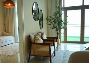 A living room with a sofa, two armchairs, a large window, and a potted plant. - Beach View 3BR Duplex Retreat in Al Reem (Abu Dhabi)