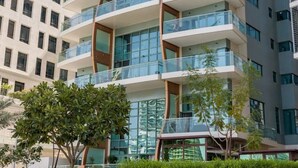 A multi-story building with balconies, large windows, and a modern architectural design. - Luxury 1BR with Gulf Views (Abu Dhabi)