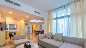 A modern living room with a sofa, a dining area, and a kitchen. - Modern 1BR Haven in Reem Island (Abu Dhabi)