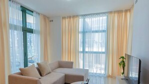 A modern living room with a sectional sofa, a round coffee table, and a flat-screen TV. - Modern 1BR Haven in Reem Island (Abu Dhabi)