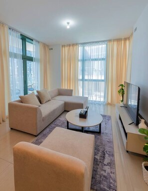 Una sala de estar moderna con un sofá modular, una mesa de centro redonda y un televisor de pantalla plana.
