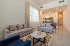 Ein modernes Wohnzimmer mit zwei Sofas, einem Couchtisch und einer Küche im Hintergrund.