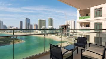 A balcony with a glass railing overlooking a beach and cityscape.
