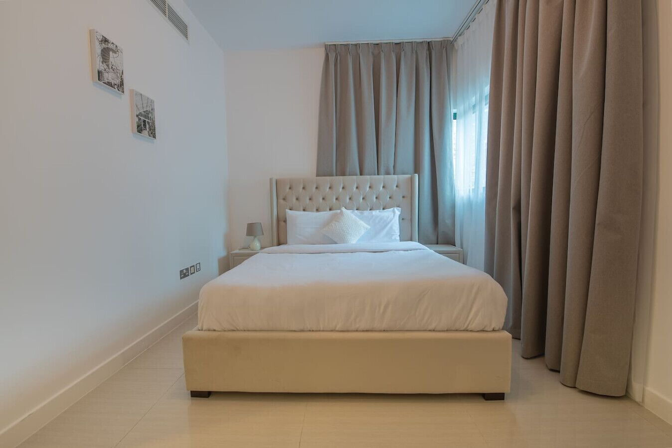 Une chambre bien rangée, avec un grand lit, une table de chevet et des rideaux.