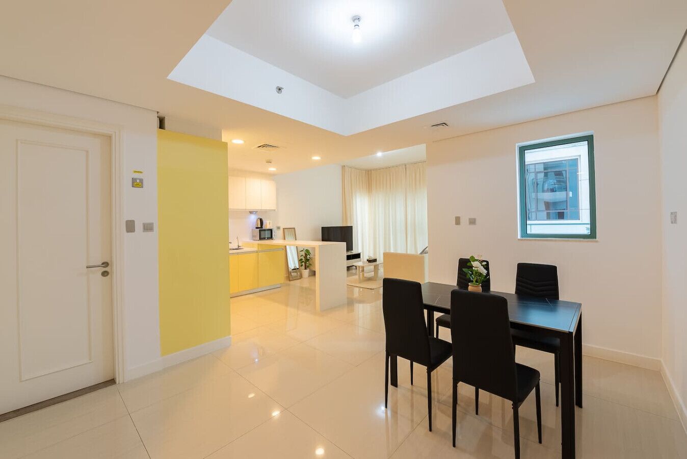 Un apartamento moderno con comedor, cocina y sala de estar con un amplio ventanal.