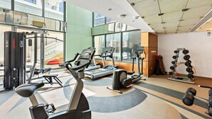 A gym with cardio machines, weightlifting equipment, and a large window providing a view of the outside.