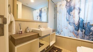 Une salle de bain moderne avec un meuble-lavabo en bois, un lavabo blanc, un miroir et un rideau de douche à motif marbré.