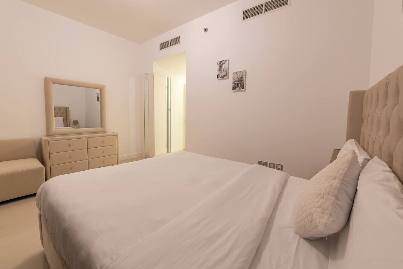 Une chambre à coucher avec un lit, une commode, un miroir et une armoire.