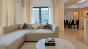 Un salon moderne avec un canapé beige, une table basse et un coin repas comprenant des chaises et une table.