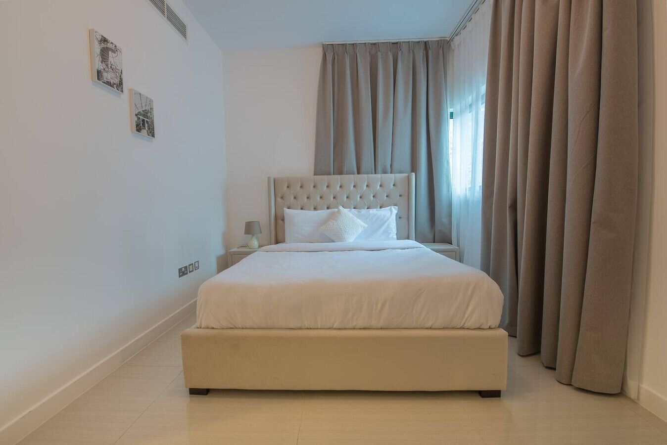 A bedroom with a large bed, a nightstand, a lamp, and curtains.