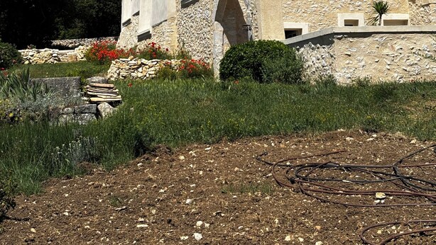 Una casa in pietra con un camino, un arco d'ingresso e una piccola finestra con persiane.