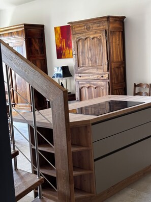 Eine Küche mit einer Holztreppe, einem Esstisch und einem Schrank.