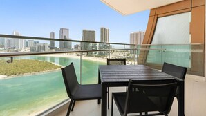 Un balcon avec une table et des chaises donnant sur une plage et offrant une vue sur les toits de la ville.
