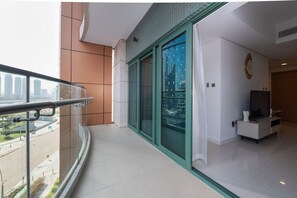 A balcony with a glass door, a white interior, and a view of a cityscape. - Elegant Escape 1BR in Al Reem Island Next to Beach (Abu Dhabi)
