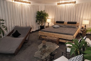 A bedroom with a bed, a chaise lounge, a glass coffee table, and a potted plant. - Fun Factory Resort (Ranchi)