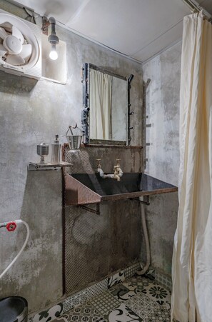 A bathroom with a single sink, a mirror, and a shower curtain.