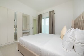 Una habitación de hotel moderna con una cama grande, un vestidor y un baño.