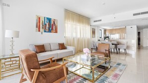 Un salon moderne comprenant un canapé, des fauteuils, une table basse en verre et un coin repas avec des chaises et une table.