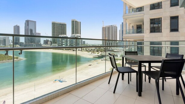 Un balcon avec vue sur une plage et sur les bâtiments de la ville.