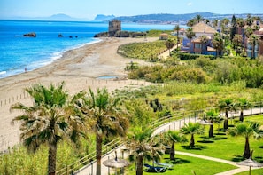Ein Küstenresort mit Strand, Palmen und einem Turm mit Blick aufs Meer.