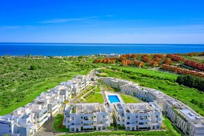 A modern resort with a central pool, arranged buildings, and a view of the sea. - 3015 Luxury Serenity Views Apartment in Estepona (Buenas Noches)