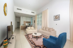 Una sala de estar moderna con un sofá, un sillón azul, una mesita de centro y un televisor.