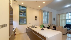 A modern kitchen with a central island, a dining area with a sofa, and a living room with a couch. - Beachfront 1BR with Huge Balcony in Al Reem Island (Abu Dhabi)