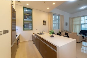 Eine moderne Küche mit Kochinsel, ein Essbereich mit Sofa und ein Wohnzimmer mit Couch.