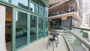 A balcony with a glass railing, a small table, and chairs, overlooking a cityscape. - Beachfront 1BR with Huge Balcony in Al Reem Island (Abu Dhabi)