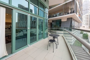 Ein Balkon mit Glasgeländer, einem kleinen Tisch und Stühlen mit Blick auf die Stadt.