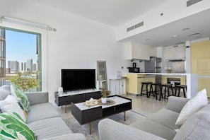 Una sala moderna con televisor de pantalla plana, sofá, mesa de centro y vistas a la ciudad.