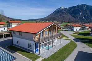 A residential building with a red-tiled roof, a balcony, and a swimming pool.