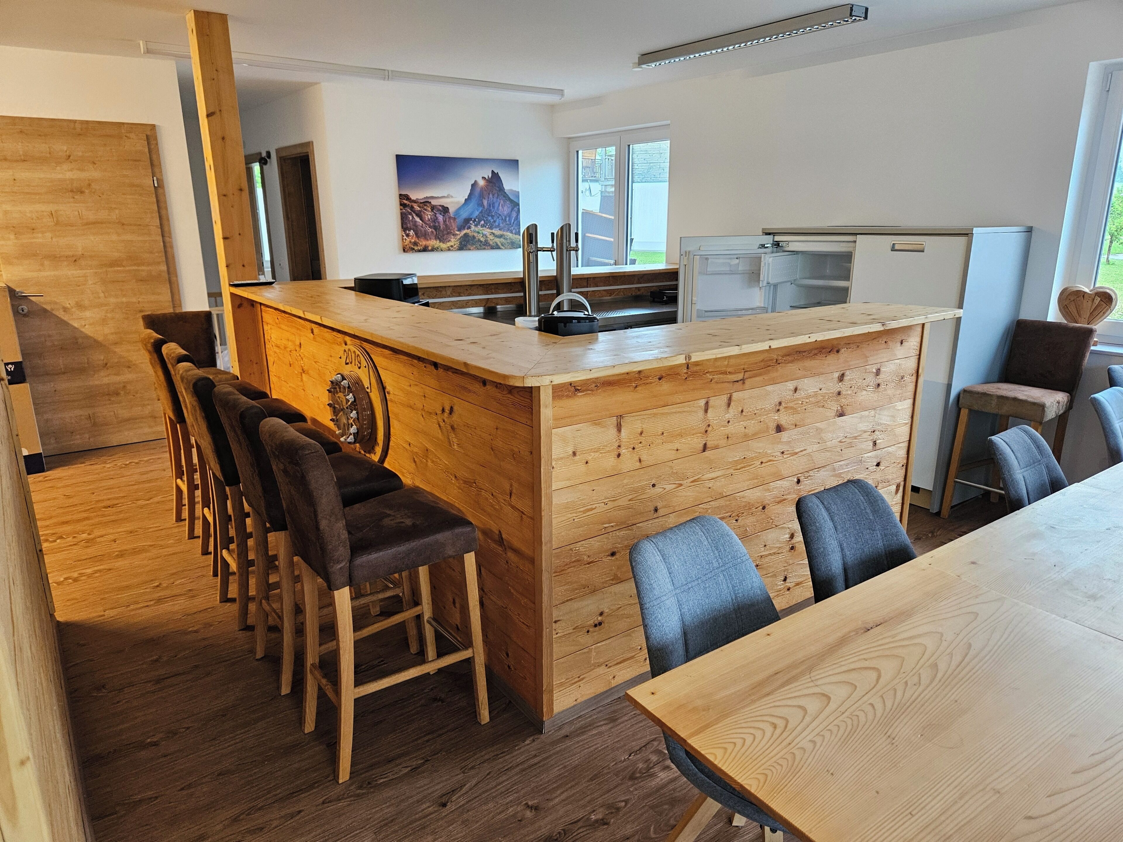 A modern kitchen with a wooden island, bar stools, and a dining table.