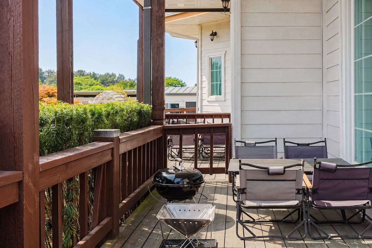 Un patio techado al aire libre con cubierta de madera, una parrilla y mobiliario exterior.