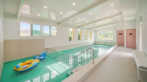 Una piscina con un puesto de socorrista, un banco y un vestuario.