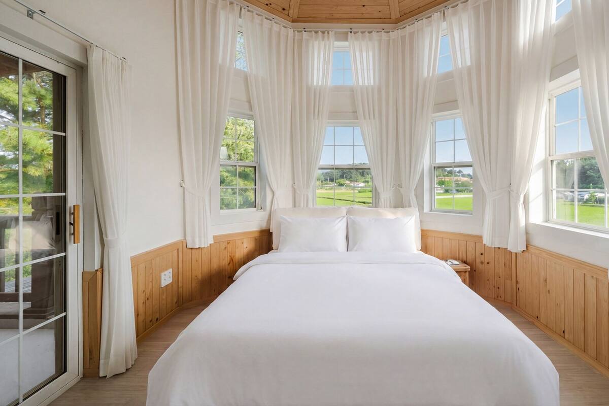 Un dormitorio con una cama grande, paneles de madera y varias ventanas con cortinas.