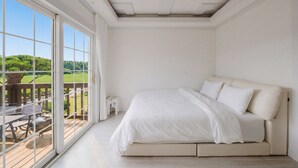Ein Schlafzimmer mit großem Fenster, einem Bett und einem kleinen Tisch.