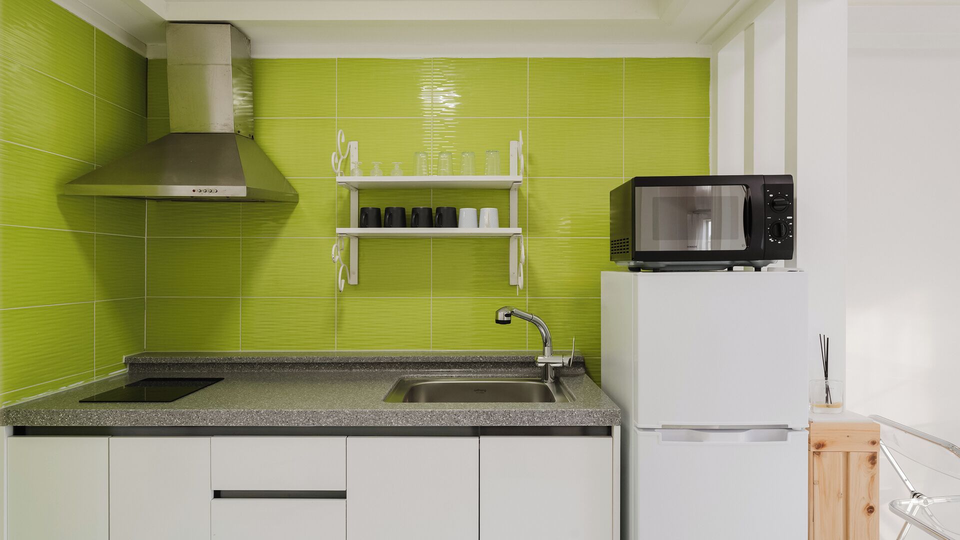 A kitchen with a stainless steel range hood, a microwave, a sink, and white cabinets.