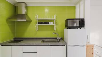 A kitchen with a stainless steel range hood, a microwave, a sink, and white cabinets.