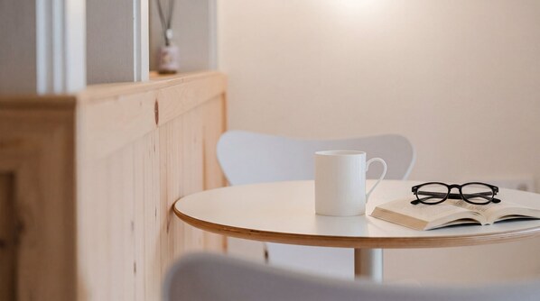Ein runder Tisch mit einer weißen Tasse, einem Brillenpaar und einem offenen Buch.