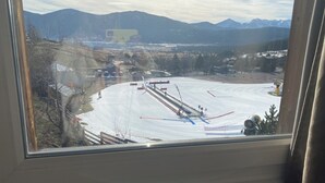 En skidbacke med en lift, träd och berg i bakgrunden.
